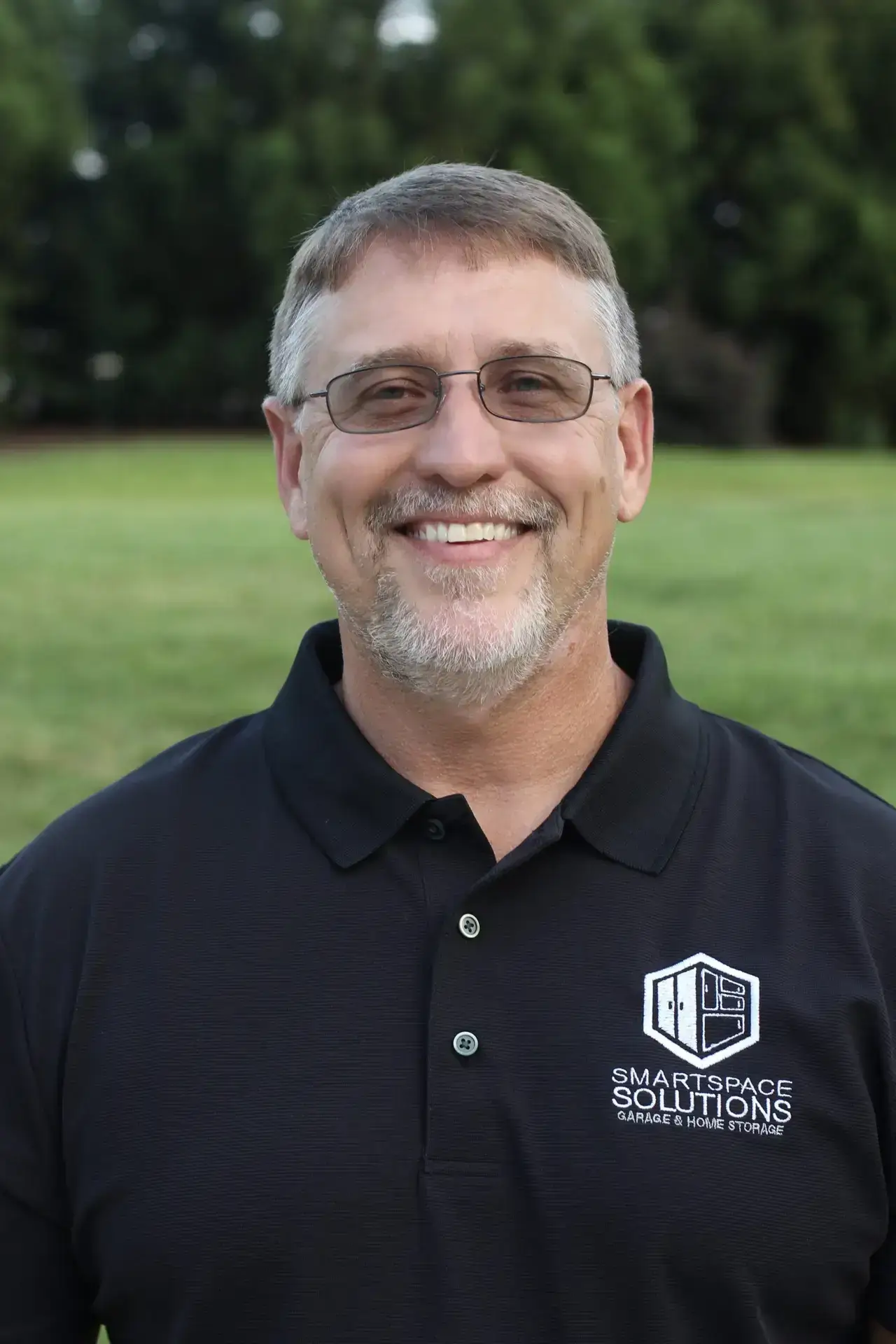 Headshot of Chris Reed, owner of SmartSpace, wearing black SmartSpace button up, smiling at camera.