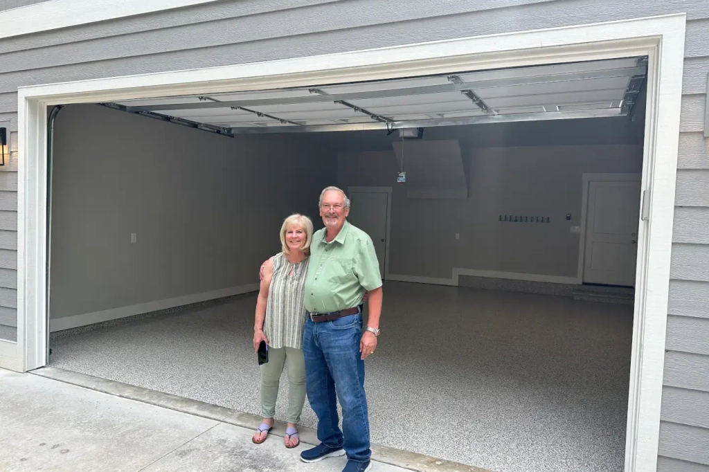 A satisfied customer in front of their newly redone garage floor.