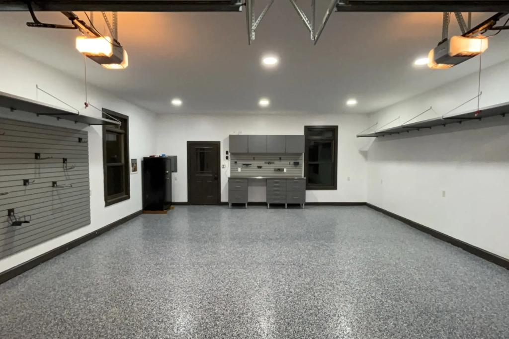 Spacious garage with polyaspartic flooring, slat wall storage, overhead shelving, and a custom workbench