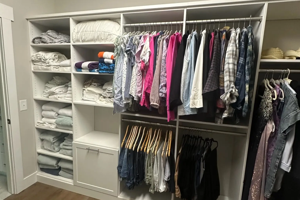 Custom walk-in closet with built-in shelving, hanging space, and storage for linens and clothing